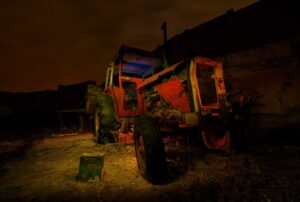 Tractor abandonado iluminado durante la noche junto a unas ruinas en un entorno rural